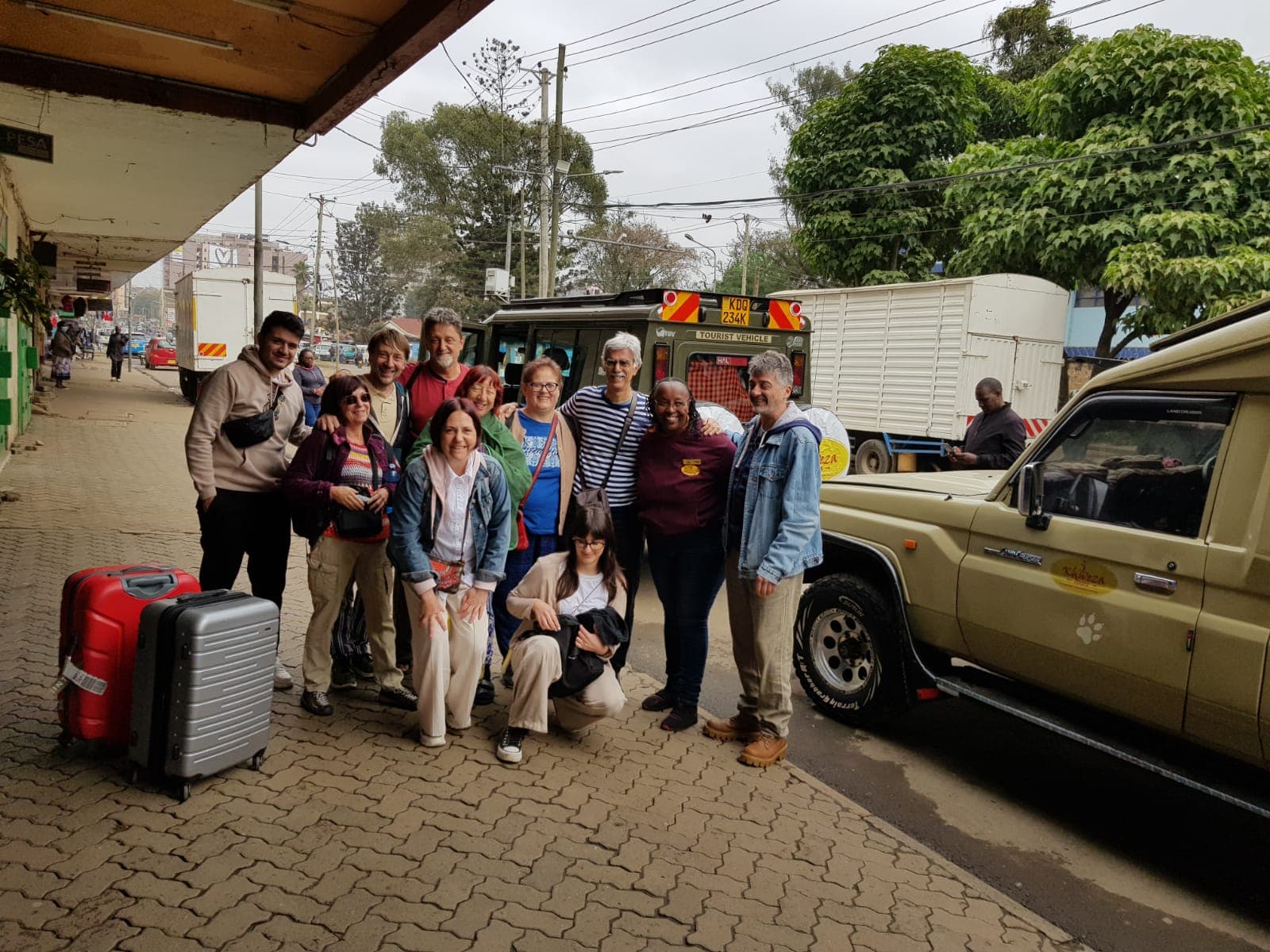 Group of travelers with their luggage beside Khweza safari vehicles in Nairobi